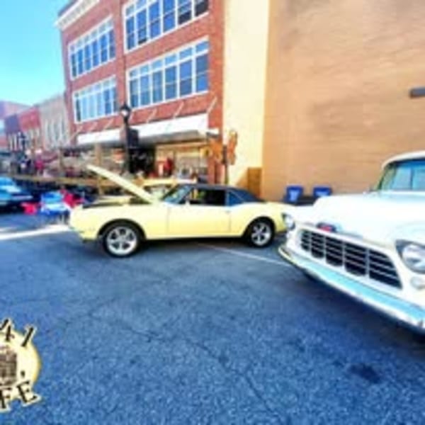 Classic cars parked on a street in front of brick buildings, with the 1841 Cafe logo.