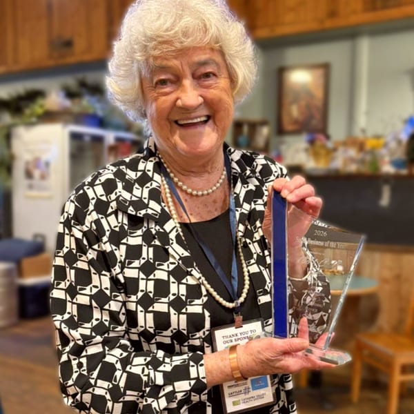 Smiling older woman with white hair holding a "Small Business of the Year" award.