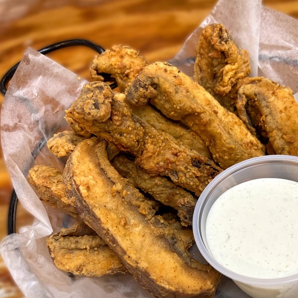 A basket of crispy fried mushrooms with a side of creamy ranch dipping sauce.