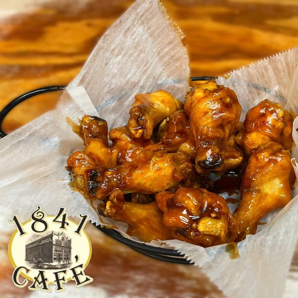 A basket of glistening, golden-brown chicken wings with a sweet and savory glaze from 1841 Cafe.