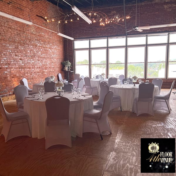 An event space with round tables, white tablecloths, chairs, and large windows at 1841 Cafe.